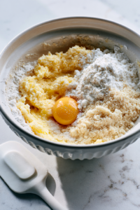 Prepare the tart dough by creaming the butter and powdered sugar until light
